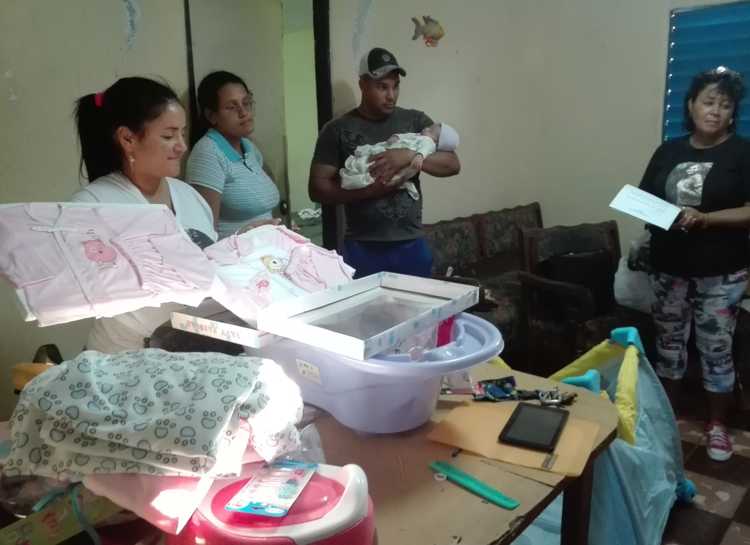 Dirigentes juveniles y de la Federación de Mujeres Cubanas en presencia de la entrega de la canastilla.